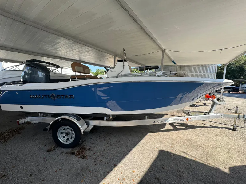 Slide: The Image of 2024 NauticStar 191 Hybrid boat on a trailer under a canopy. - 1