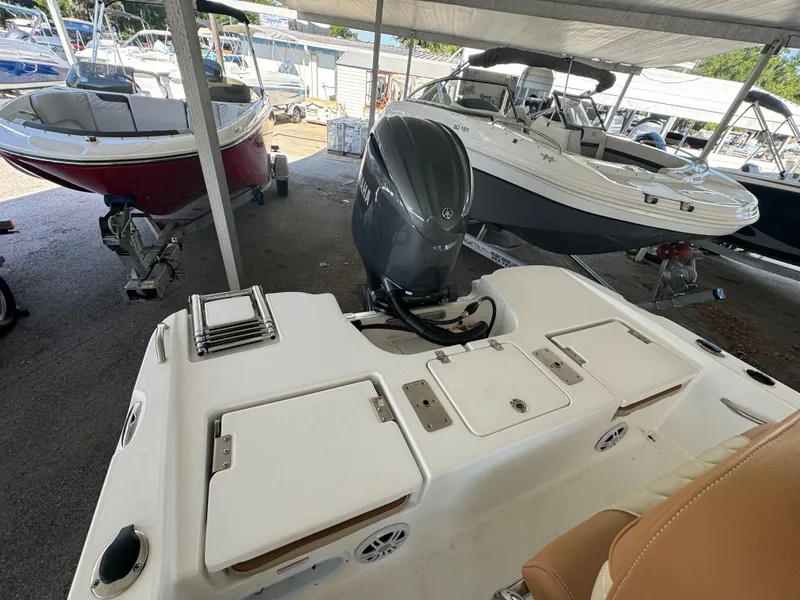 Slide: The Image of 2024 NauticStar 191 Hybrid boat with outboard motor in a covered marina. - 8