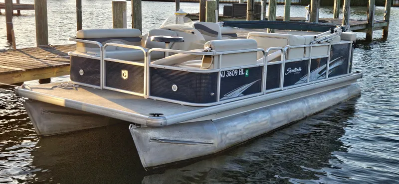 Slide: The Image of 2018 Sweetwater Sunrise 226 C pontoon boat docked on calm water. - 0