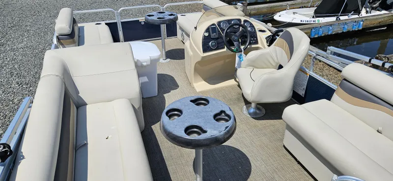 Slide: The Image of 2018 Sweetwater Sunrise 226 C pontoon boat interior with beige seating and cup holders. - 7