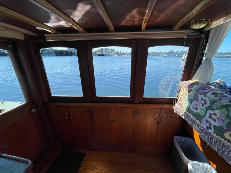 Slide: The Image of Interior view of a 1931 Jensen Cruiser boat with wooden paneling and waterfront scenery. - 15