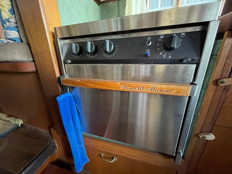 Slide: The Image of Stainless steel marine oven with wooden handle and blue towel, inside a 1931 Jensen Cruiser. - 19