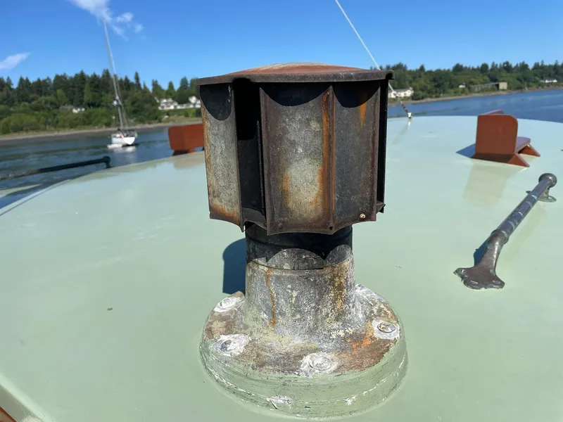 Slide: The Image of Rusty vent on 1931 Jensen Cruiser boat deck, with scenic water and trees in background. - 49
