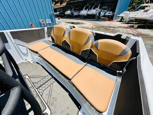 Slide: The Image of 2023 Scarab 255 Open ID boat with tan and black seating in a marina. - 10
