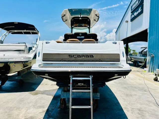 Slide: The Image of 2023 Scarab 255 Open ID boat at a marina, rear view with ladder. - 2