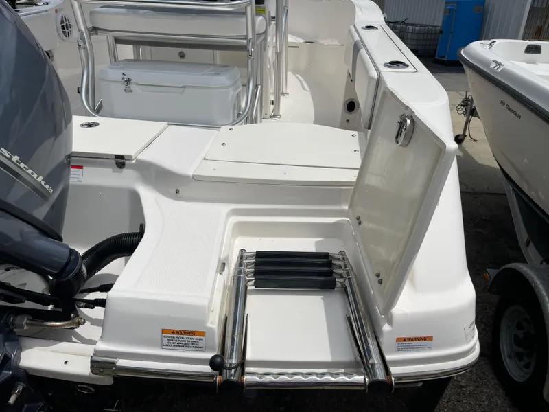 Slide: The Image of 2021 Robalo R180 Center Console boat with open storage compartment and ladder. - 28