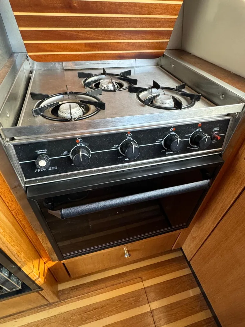 Slide: The Image of 1999 Bayliner 4087 yacht kitchen with a three-burner stove and oven. - 13