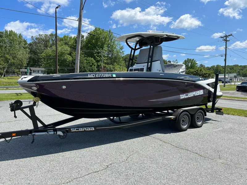 The Image of 2021 Scarab 255 Open ID boat on trailer, parked outdoors under blue sky. - 0