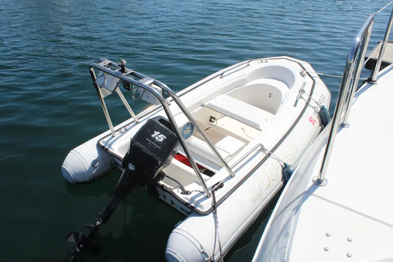 Slide: The Image of Inflatable boat with outboard motor docked on water, near Trojan 440 Express, 1996 model. - 11