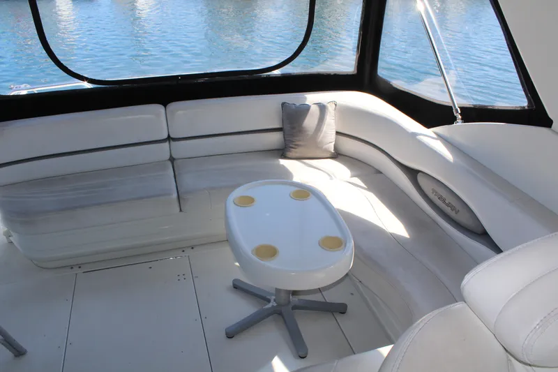 Slide: The Image of 1996 Trojan 440 Express yacht interior with white seating and table, overlooking water. - 12