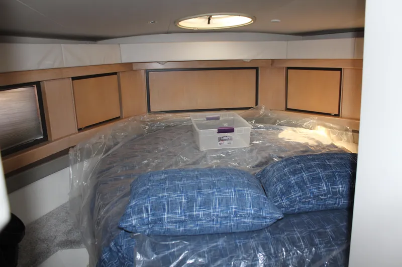Slide: The Image of 1996 Trojan 440 Express cabin with blue bedding and storage box. - 44