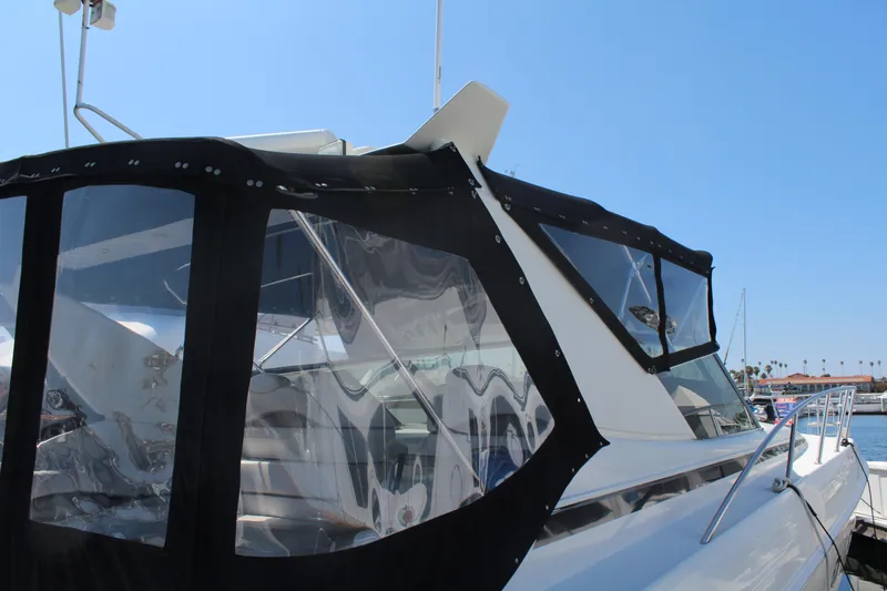 Slide: The Image of 1996 Trojan 440 Express yacht with black canvas enclosure, docked under clear blue sky. - 8