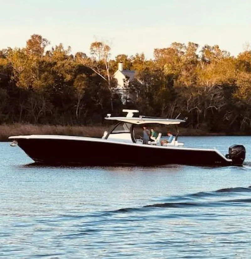 Slide: The Image of 2019 Blackwater 43SF boat cruising on a calm river with lush trees in the background. - 43
