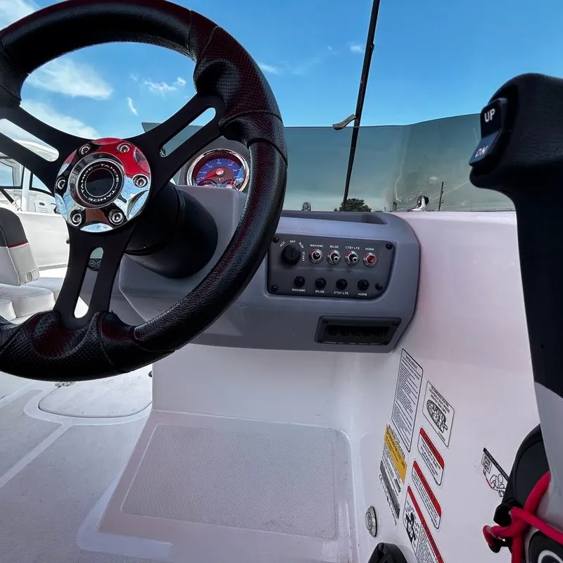 Slide: The Image of Steering wheel and control panel of a 2022 Tahoe T18 boat under a clear blue sky. - 12