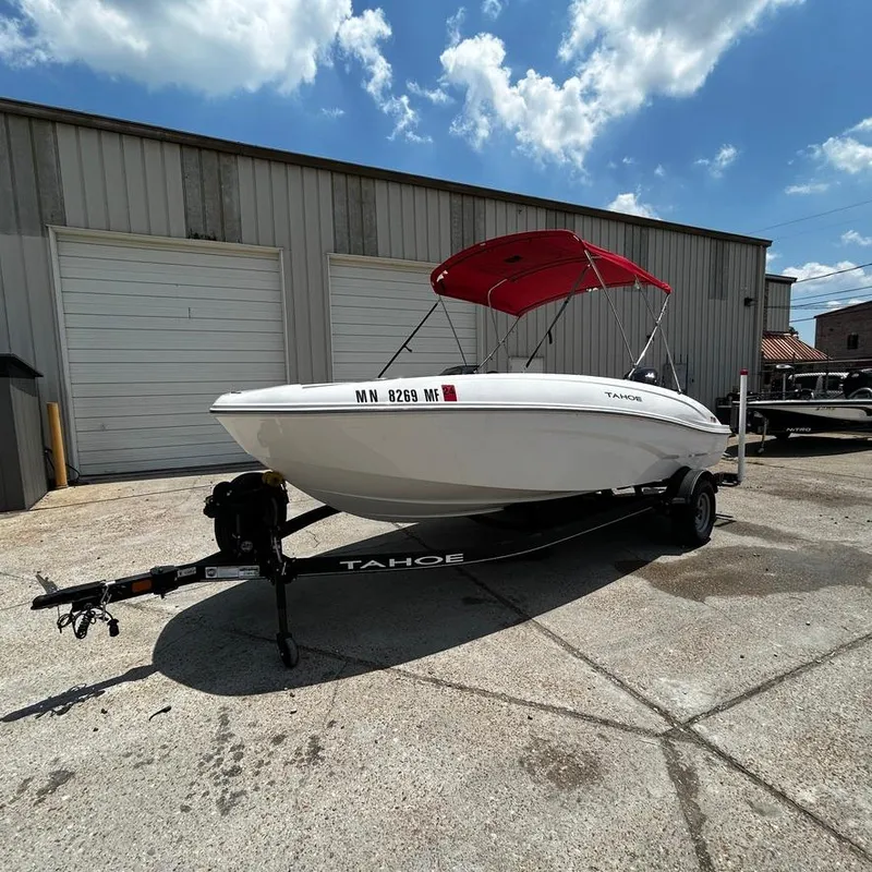 Slide: The Image of 2022 Tahoe T18 boat with red canopy on trailer, parked outside a garage. - 7