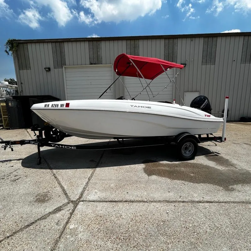 Slide: The Image of 2022 Tahoe T18 boat with red canopy on trailer outside warehouse. - 9