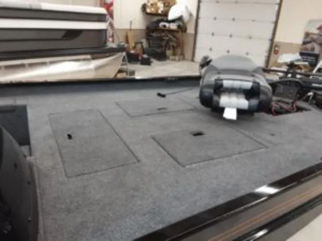 Slide: The Image of 2023 Lowe RX1860 boat interior with storage compartments and motor in a garage. - 5