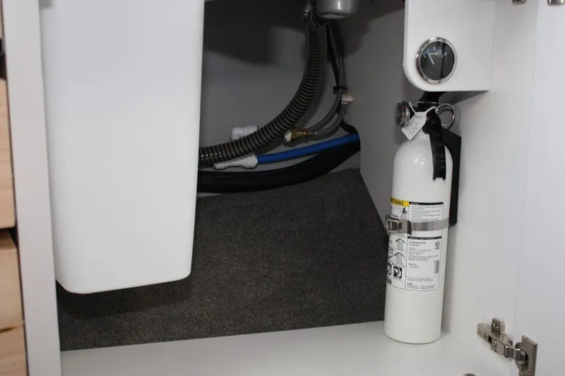 Slide: The Image of Fire extinguisher and plumbing inside a 2025 Formula 350 Sun Sport boat cabinet. - 49