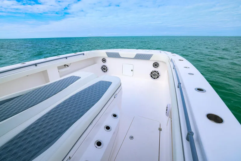 Slide: The Image of 2024 Invincible 46 Catamaran deck with ocean view, featuring cushioned seating and speakers. - 12