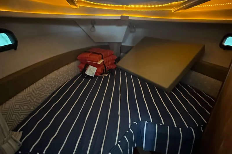 Slide: The Image of 2021 Ranger Tugs R-27 cabin interior with striped bedding and ambient lighting. - 11