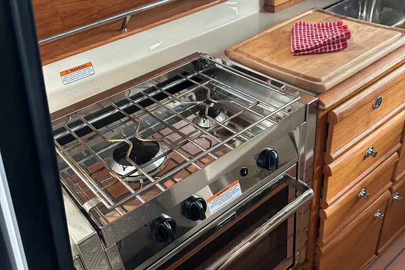 Slide: The Image of 2021 Ranger Tugs R-27 kitchen with stove, oven, and wooden cabinetry. - 8