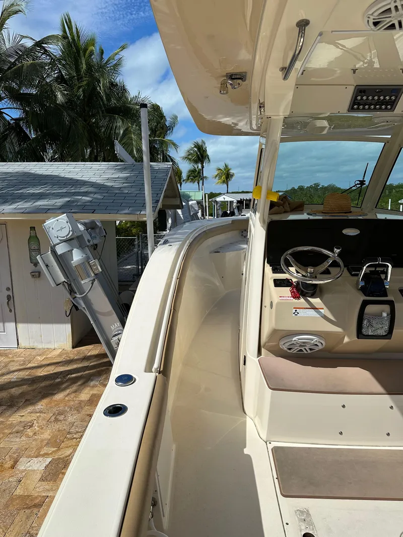 Slide: The Image of 2018 Scout 300 LXF boat docked near a tropical setting with palm trees. - 13