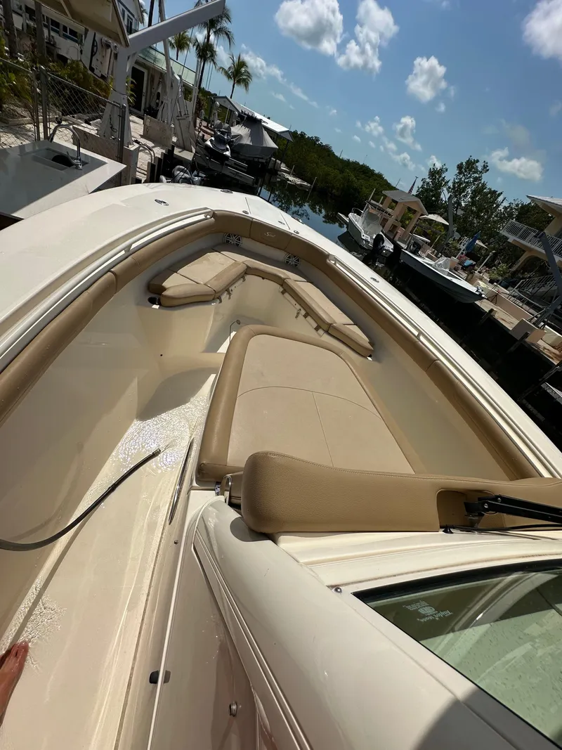 Slide: The Image of 2018 Scout 300 LXF boat with beige seating, docked under a sunny sky. - 14