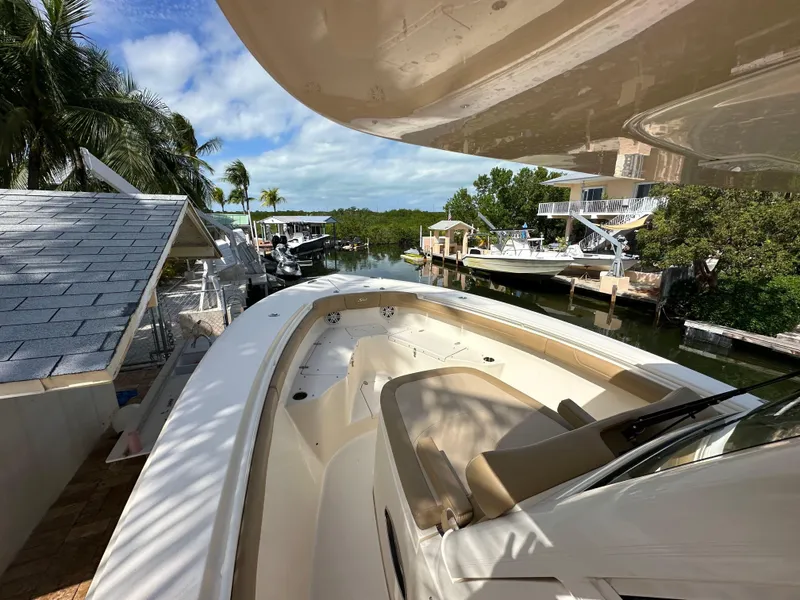 Slide: The Image of 2018 Scout 300 LXF boat docked near waterfront homes and lush greenery. - 15