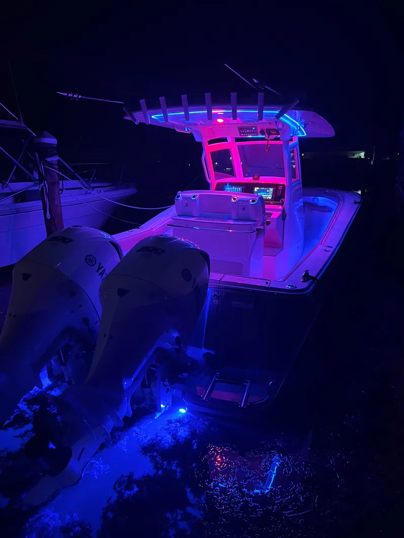 Slide: The Image of 2018 Scout 300 LXF boat with vibrant night lighting and twin Yamaha engines. - 21