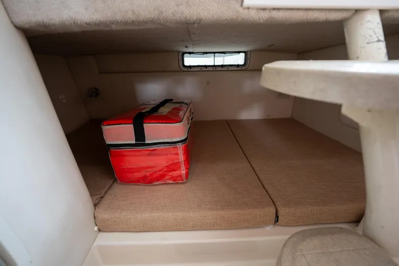Slide: The Image of 2003 Aquasport 275 Explorer cabin interior with storage compartment and red cooler. - 25