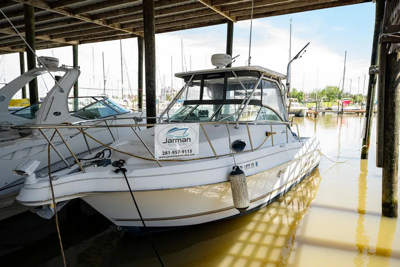 Slide: The Image of 2003 Aquasport 275 Explorer boat docked in a marina under a covered structure. - 3