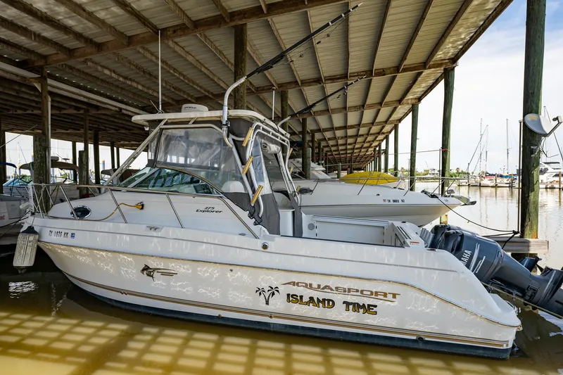 Slide: The Image of 2003 Aquasport 275 Explorer boat docked under a covered marina. - 5