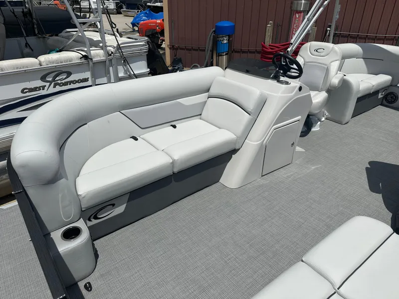 Slide: The Image of 2022 Crest Classic DLX 200 SLC pontoon boat interior with plush seating and helm station. - 4
