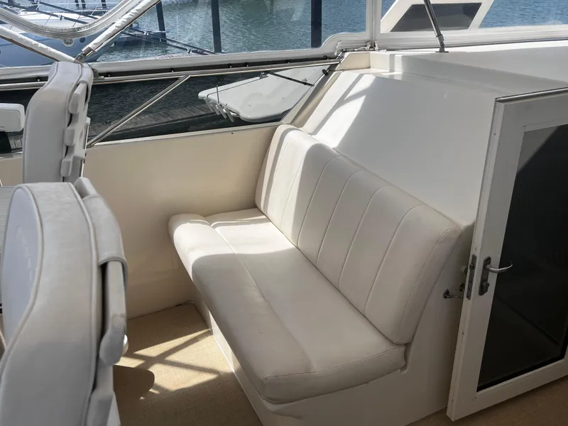 Slide: The Image of 1991 Hatteras 52 Cockpit Motoryacht interior with white seating and window view. - 17