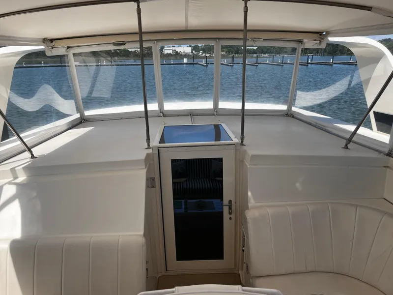 Slide: The Image of 1991 Hatteras 52 Cockpit Motoryacht interior with white seating and panoramic windows. - 18