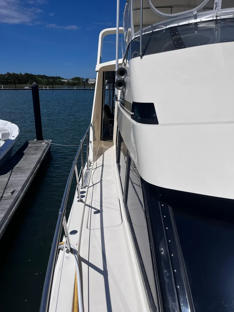 Slide: The Image of 1991 Hatteras 52 Cockpit Motoryacht docked, showcasing sleek design and spacious deck. - 2