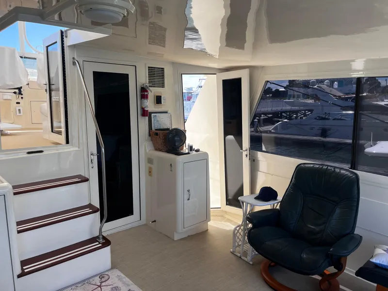 Slide: The Image of Interior of 1991 Hatteras 52 Cockpit Motoryacht with seating and stairs, dock view outside. - 23