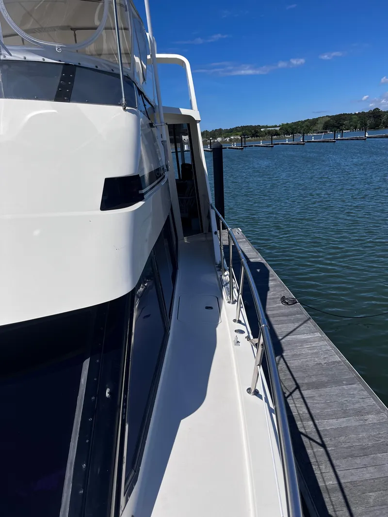 Slide: The Image of 1991 Hatteras 52 Cockpit Motoryacht docked by a serene waterfront. - 3