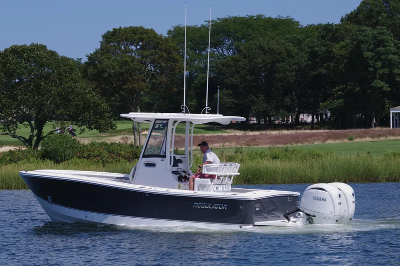 Slide: The Image of 2024 Regulator 23 boat cruising on a lake with lush greenery in the background. - 11