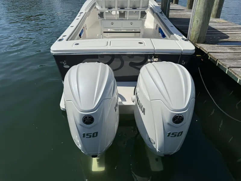 Slide: The Image of 2024 Regulator 23 boat with twin Yamaha 150 engines docked on calm water. - 12