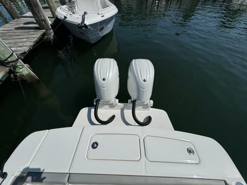 Slide: The Image of 2024 Regulator 23 boat with dual outboard motors docked on calm water. - 15