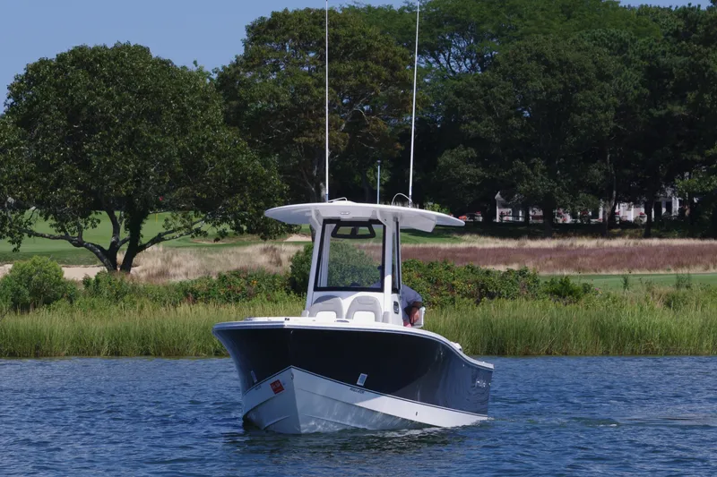 Slide: The Image of 2024 Regulator 23 boat on calm water near lush greenery. - 2