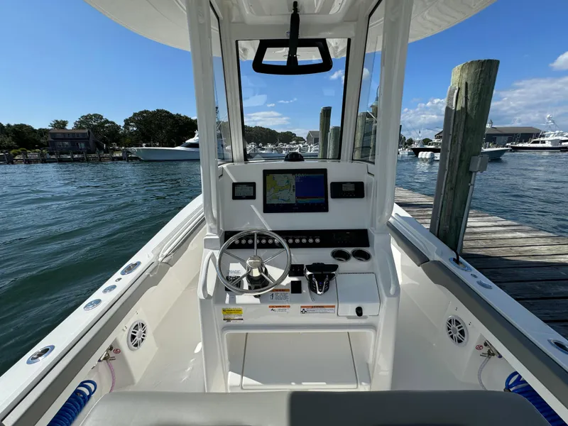 Slide: The Image of 2024 Regulator 23 boat console with steering wheel and navigation system at dock. - 28