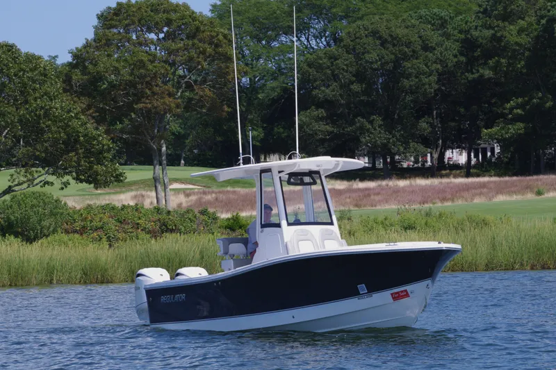 Slide: The Image of 2024 Regulator 23 boat cruising on a serene lake with lush greenery. - 5