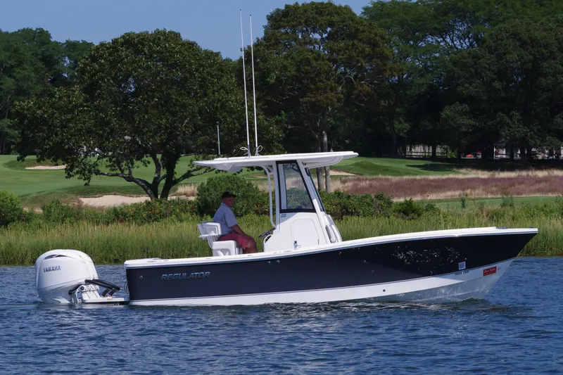 Slide: The Image of 2024 Regulator 23 boat cruising on a lake with lush greenery in the background. - 6