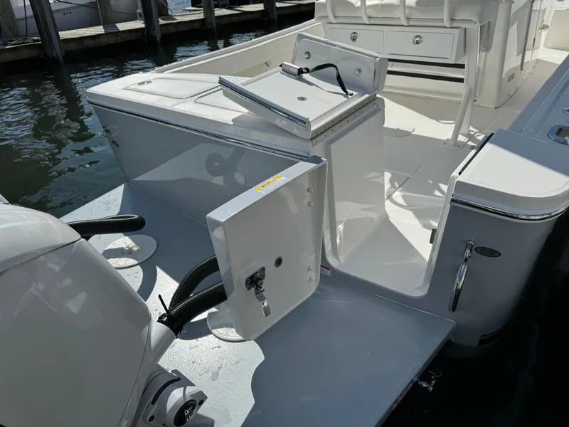 Slide: The Image of 2024 Regulator 23 boat stern with open hatch and motor, docked in sunlight. - 11