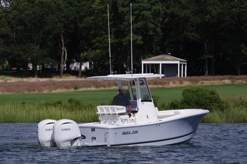 Slide: The Image of 2024 Regulator 23 boat with dual Yamaha engines on a scenic waterway. - 2