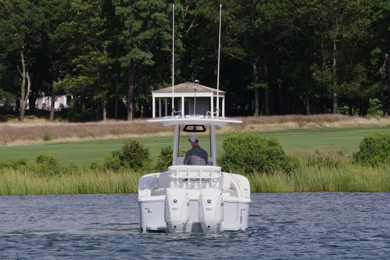 Slide: The Image of 2024 Regulator 23 boat cruising on a lake with lush greenery in the background. - 3