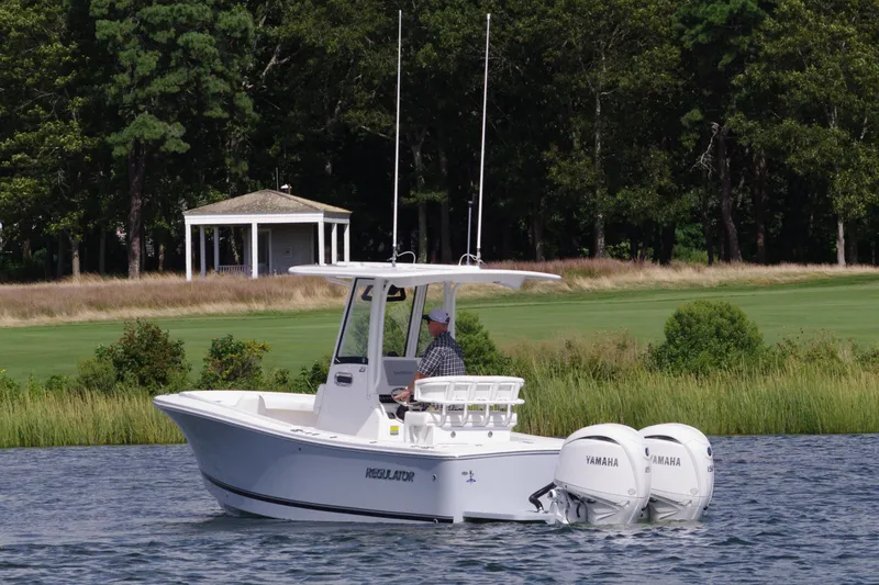 Slide: The Image of 2024 Regulator 23 boat with dual Yamaha engines on a scenic lake. - 4