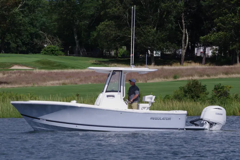Slide: The Image of 2024 Regulator 23 boat on a calm lake with lush greenery in the background. - 5